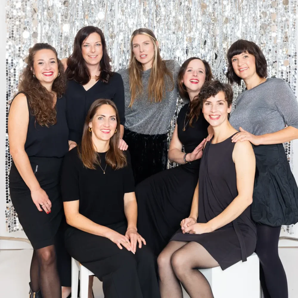 Gruppe von Frauen vor glitzerndem Hintergrund in schwarzer Kleidung