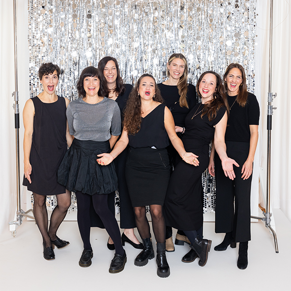 Gruppe fröhlicher Frauen vor silbernem Hintergrund