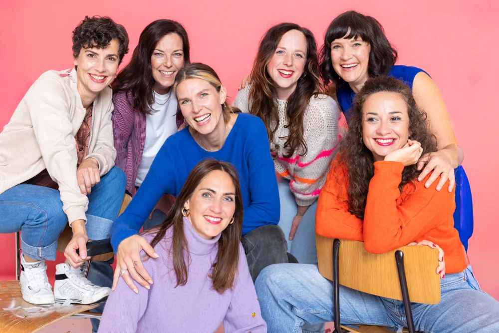 Gruppe von lächelnden Frauen vor rosa Hintergrund