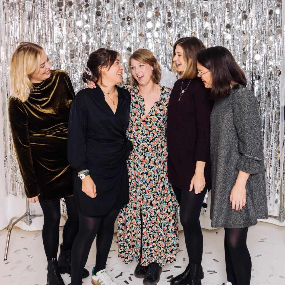 Gruppe von Frauen lächelt fröhlich vor einem silbernen Fotohintergrund
