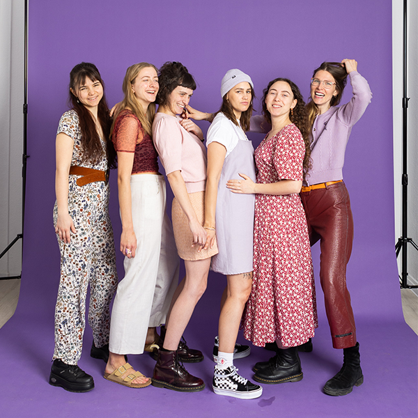 Gruppe junger Frauen vor lila Hintergrund lächelnd