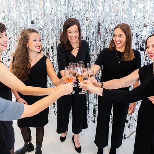 Gruppe von Frauen stößt mit Sekt an vor glitzerndem Hintergrund